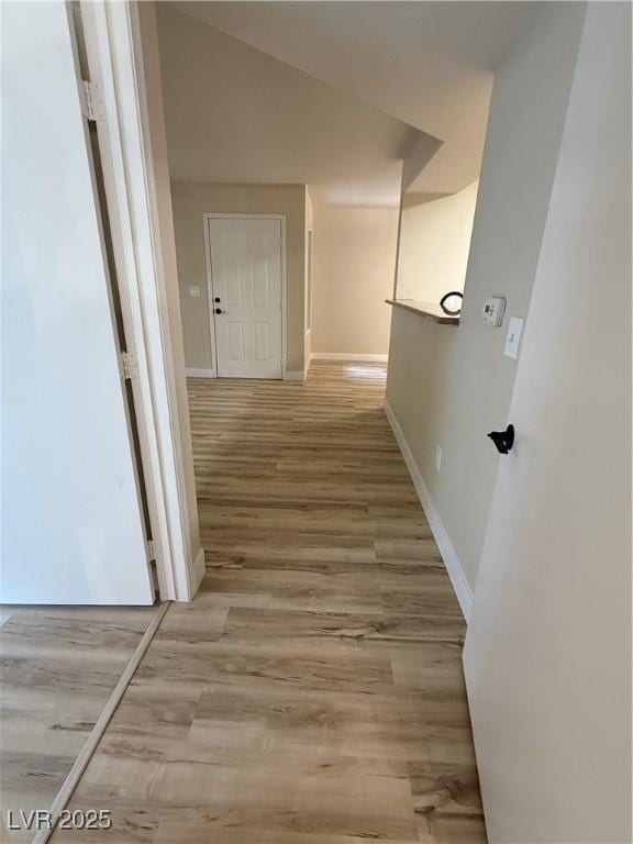 corridor featuring baseboards and light wood finished floors