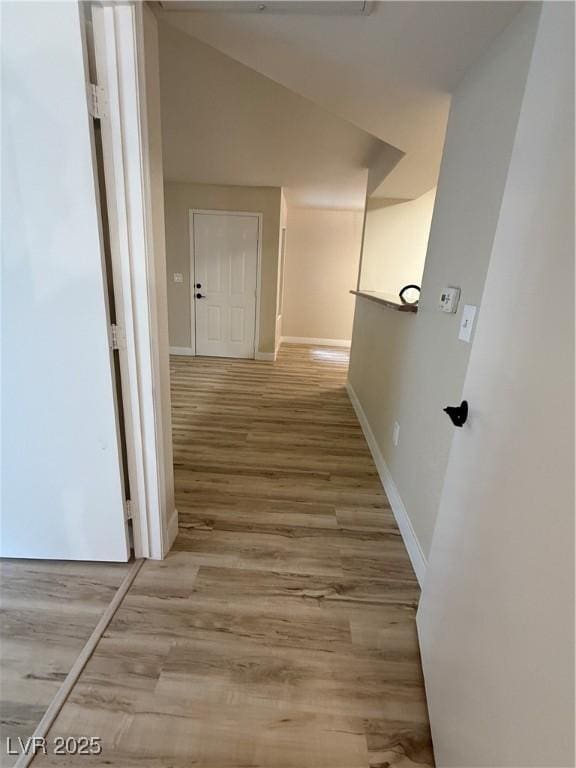 hallway featuring baseboards and light wood-style flooring