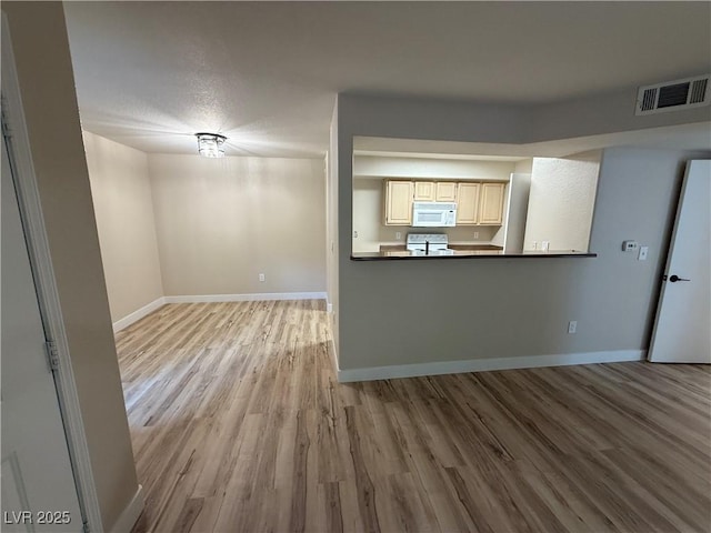 unfurnished living room with baseboards, visible vents, and wood finished floors