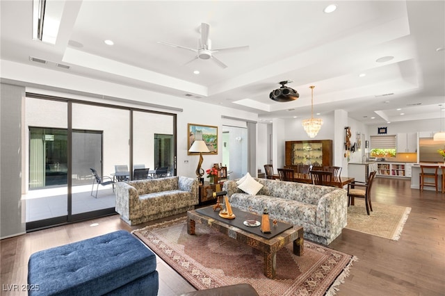 15 Gemstar Ln, Las Vegas, NV 89135 - living room with a tray ceiling, visible vents, wood finished floors, and ceiling fan with notable chandelier