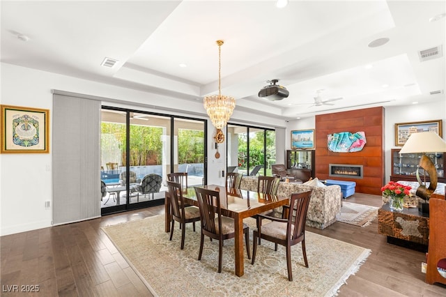 15 Gemstar Ln, Las Vegas, NV 89135 - dining space featuring visible vents, a fireplace, wood finished floors, a raised ceiling, and ceiling fan with notable chandelier