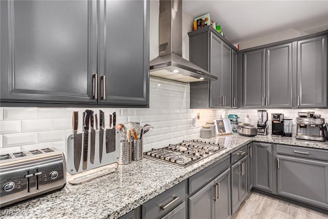 39 Castleton Tower Ct, Henderson, NV 89011 - kitchen with wall chimney range hood, light stone countertops, decorative backsplash, and stainless steel gas stovetop