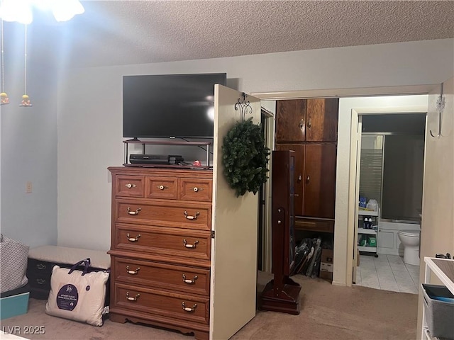 bedroom featuring light carpet, a textured ceiling, ensuite bathroom, and a closet