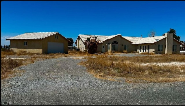 view of front of property with stucco siding, gravel driveway, and a tile roof