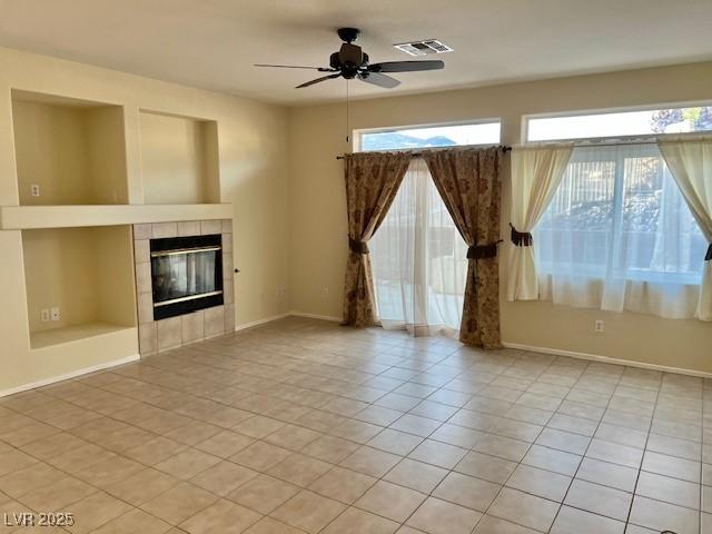 3349 Partridge Run St, Laughlin, NV 89029 - unfurnished living room featuring ceiling fan, light tile patterned flooring, a tile fireplace, and baseboards