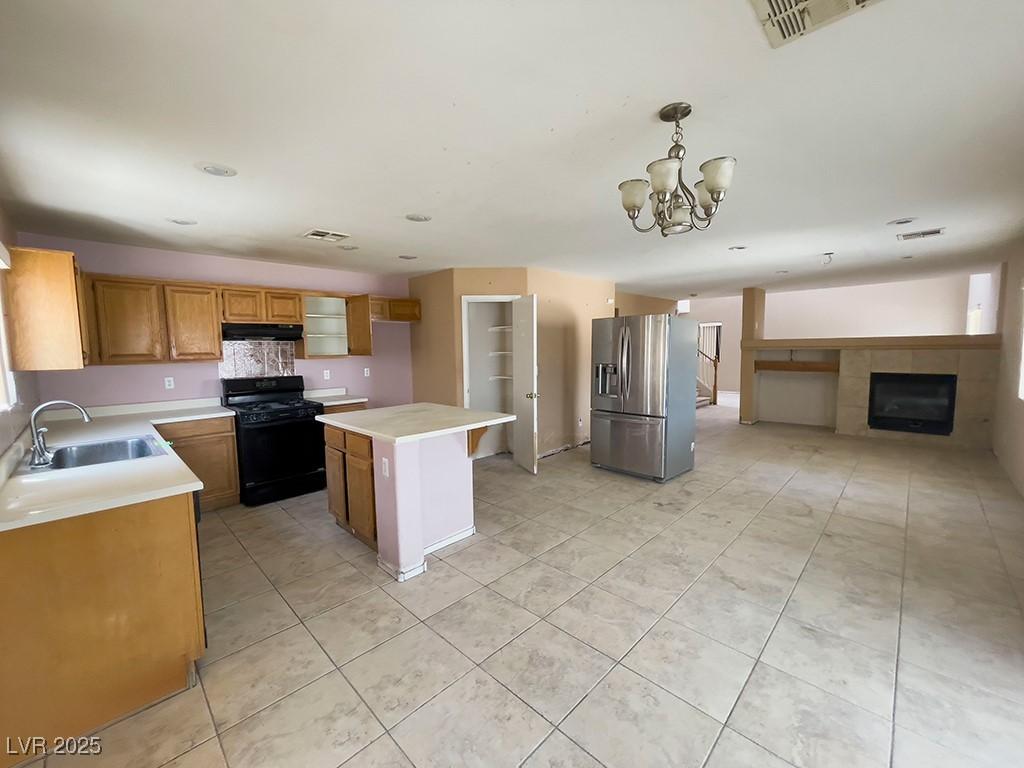 6726 Montezuma Castle Ln, North Las Vegas, NV 89084 - kitchen featuring black gas range oven, stainless steel fridge, a sink, exhaust hood, and light countertops