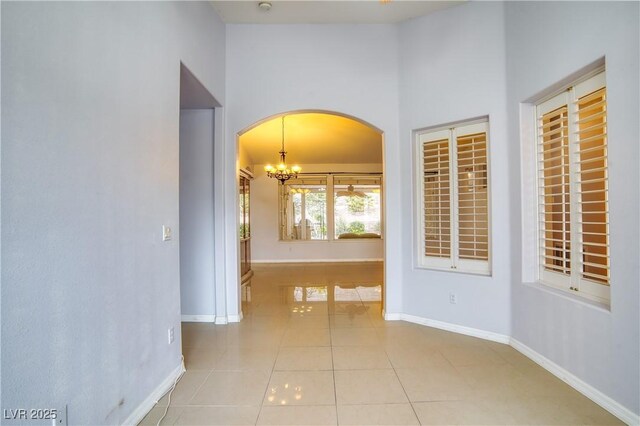 2383 Rainswept Ave, Henderson, NV 89052 - hallway featuring baseboards, arched walkways, a towering ceiling, and tile patterned flooring
