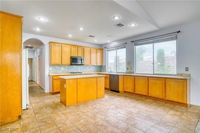 2383 Rainswept Ave, Henderson, NV 89052 - kitchen featuring light countertops, arched walkways, stainless steel appliances, tasteful backsplash, and visible vents