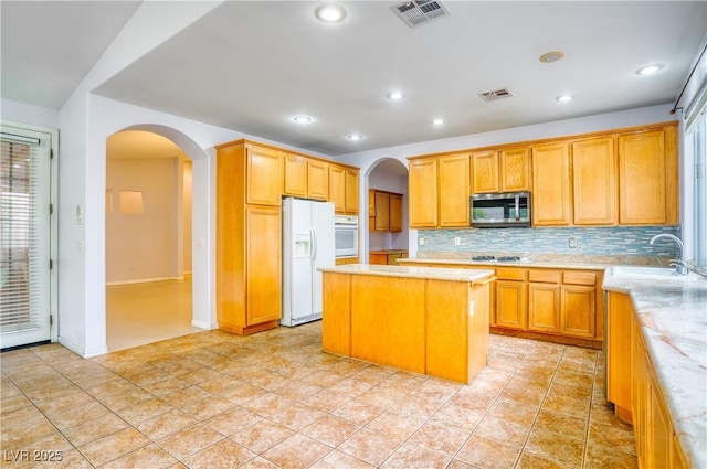 2383 Rainswept Ave, Henderson, NV 89052 - kitchen with white appliances, arched walkways, visible vents, and a sink