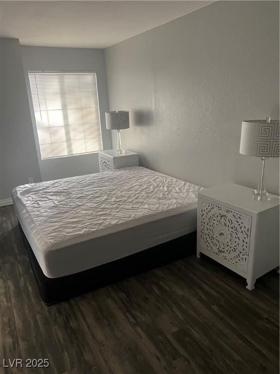 bedroom with baseboards and dark wood-type flooring
