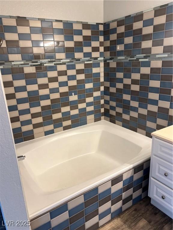 full bath with a bathtub, wood finished floors, and vanity