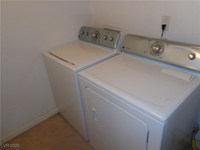 washroom featuring laundry area, baseboards, light tile patterned floors, and washing machine and dryer