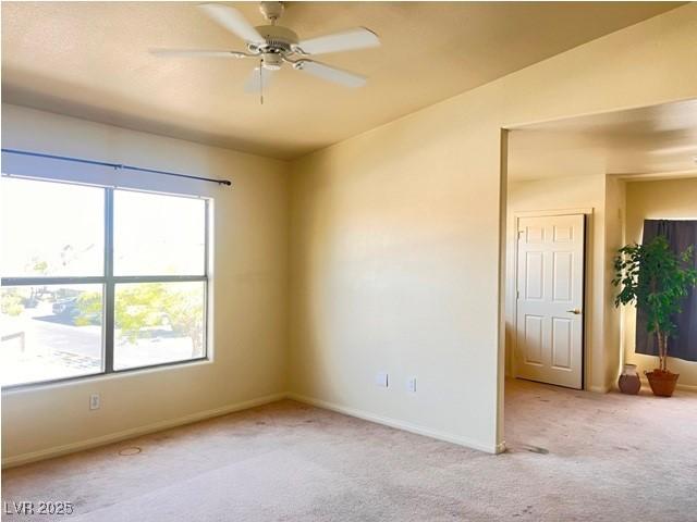 carpeted empty room featuring a ceiling fan and baseboards