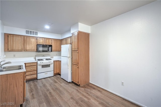 5710 E Tropicana Ave Unit 1017, Las Vegas, NV 89122 - kitchen featuring a sink, white appliances, light wood-type flooring, visible vents, and light countertops
