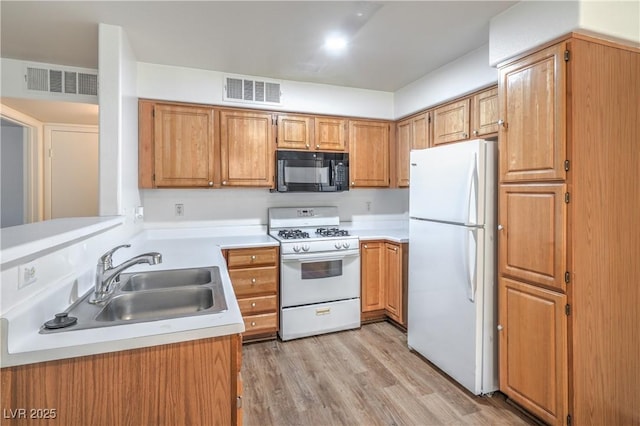5710 E Tropicana Ave Unit 1017, Las Vegas, NV 89122 - kitchen with a sink, white appliances, visible vents, light countertops, and light wood-style floors
