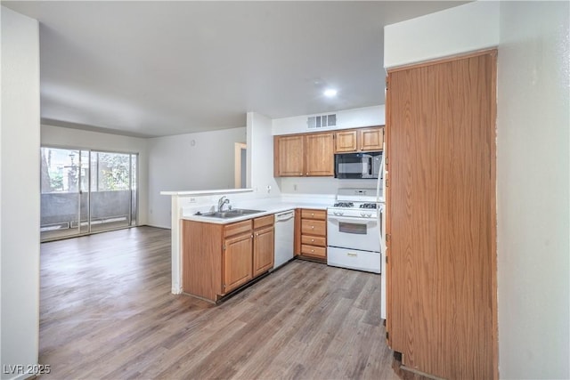5710 E Tropicana Ave Unit 1017, Las Vegas, NV 89122 - kitchen with a sink, a peninsula, white appliances, visible vents, and light wood-style flooring