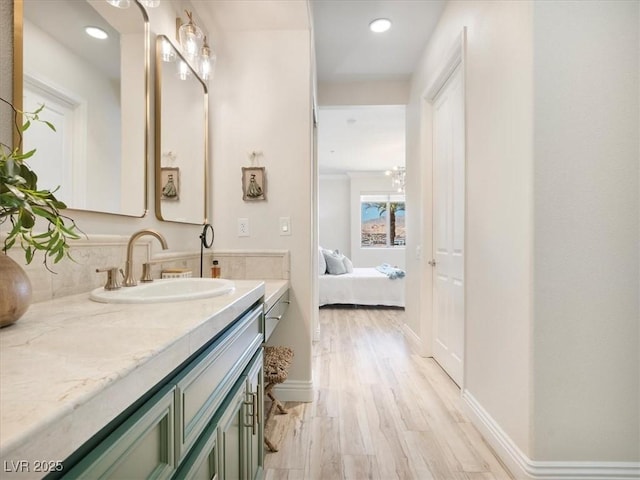 ensuite bathroom with vanity, recessed lighting, baseboards, and wood finished floors