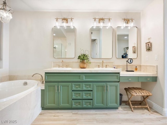 bathroom with double vanity, a garden tub, wood finished floors, and a sink