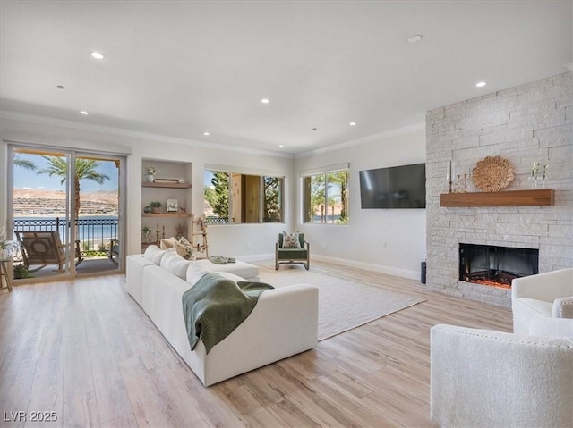 living room with light wood finished floors, a fireplace, and ornamental molding