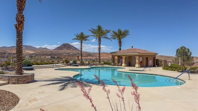 community pool featuring fence, a patio area, and a mountain view