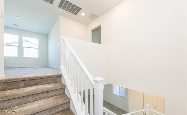 staircase with plenty of natural light, visible vents, and carpet floors