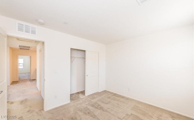 unfurnished bedroom featuring light colored carpet, a closet, and visible vents