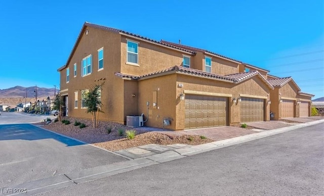 view of front of property with cooling unit, stucco siding, a tiled roof, and a mountain view