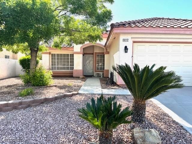 mediterranean / spanish house featuring an attached garage, a tiled roof, stucco siding, and fence