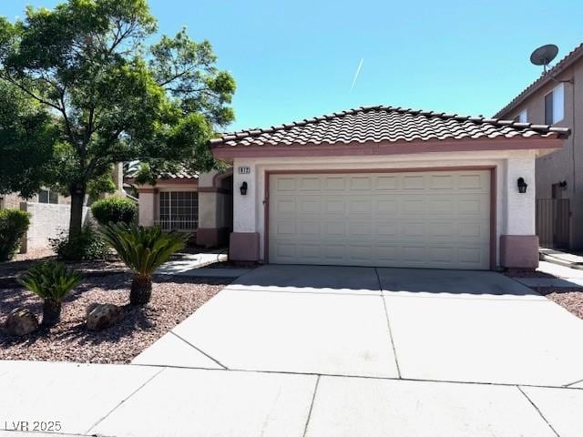 mediterranean / spanish-style home featuring concrete driveway, stucco siding, a tiled roof, and a garage