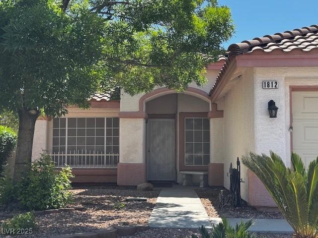 property entrance featuring a tiled roof and stucco siding