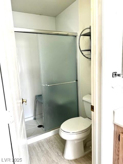 bathroom featuring a stall shower, vanity, toilet, and wood finished floors