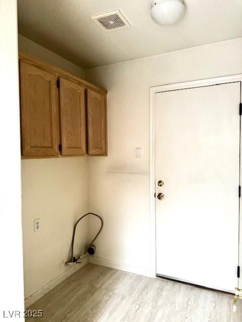 laundry area featuring cabinet space, visible vents, light wood-style flooring, and baseboards