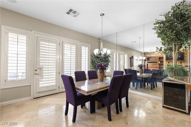 dining area with baseboards, a notable chandelier, visible vents, and beverage cooler