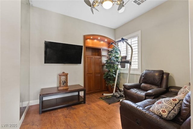 living area with visible vents, wood finished floors, baseboards, and a notable chandelier
