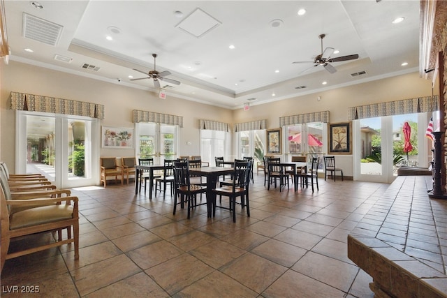 dining room featuring a tray ceiling, a towering ceiling, a ceiling fan, and visible vents