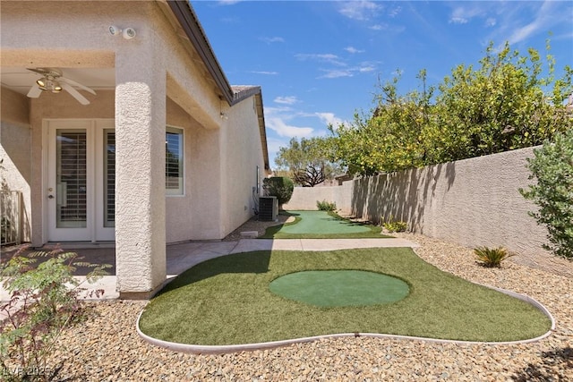 view of yard featuring central air condition unit, ceiling fan, and a fenced backyard