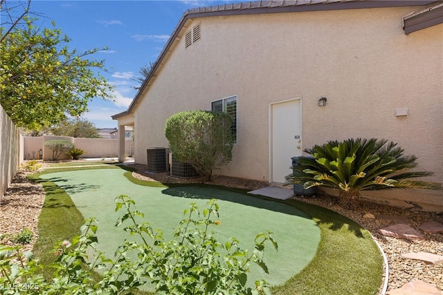 rear view of house featuring central AC, stucco siding, and a fenced backyard