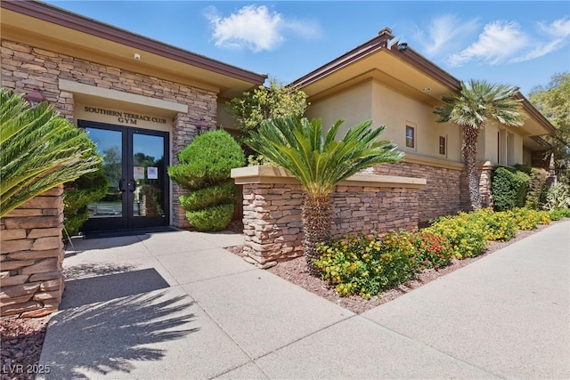 doorway to property featuring stucco siding, french doors, and stone siding