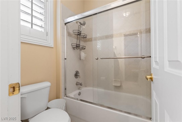 bathroom with toilet and shower / bath combination with glass door