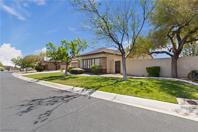 ranch-style home with driveway, fence, an attached garage, stucco siding, and a front yard