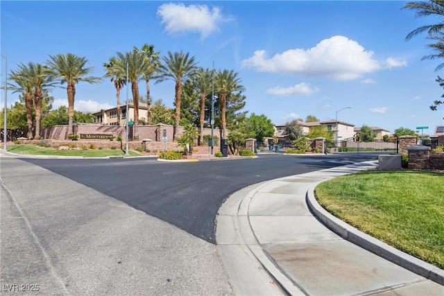view of street featuring street lights, a gate, a residential view, sidewalks, and curbs