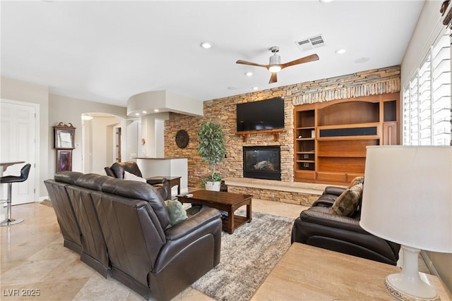 living room with a fireplace, visible vents, ceiling fan, arched walkways, and recessed lighting