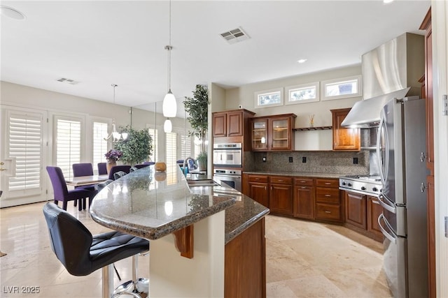 kitchen with a healthy amount of sunlight, brown cabinetry, visible vents, and appliances with stainless steel finishes