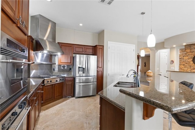 kitchen with a sink, wall chimney range hood, tasteful backsplash, a kitchen breakfast bar, and appliances with stainless steel finishes