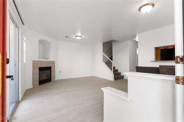 4076 Rocky Beach Dr, Las Vegas, NV 89115 - unfurnished living room featuring stairway, light wood-type flooring, visible vents, and a tile fireplace