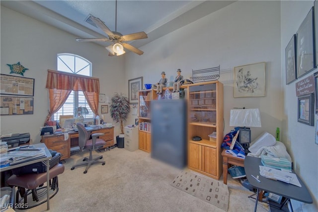 carpeted office space featuring ceiling fan and a towering ceiling
