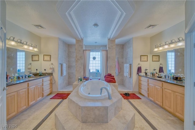 full bathroom with a sink, a textured ceiling, a bath, and visible vents