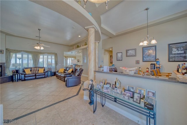 living room featuring decorative columns, baseboards, tile patterned flooring, and ceiling fan with notable chandelier