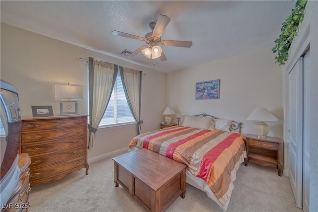 bedroom with a ceiling fan, a closet, visible vents, baseboards, and light colored carpet