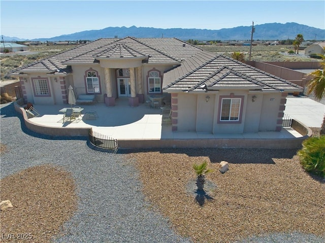 view of front of house with stucco siding, a patio area, a tiled roof, and a mountain view